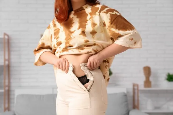 Image of woman trying to do her trousers up after pregnancy weight gain Willenhall